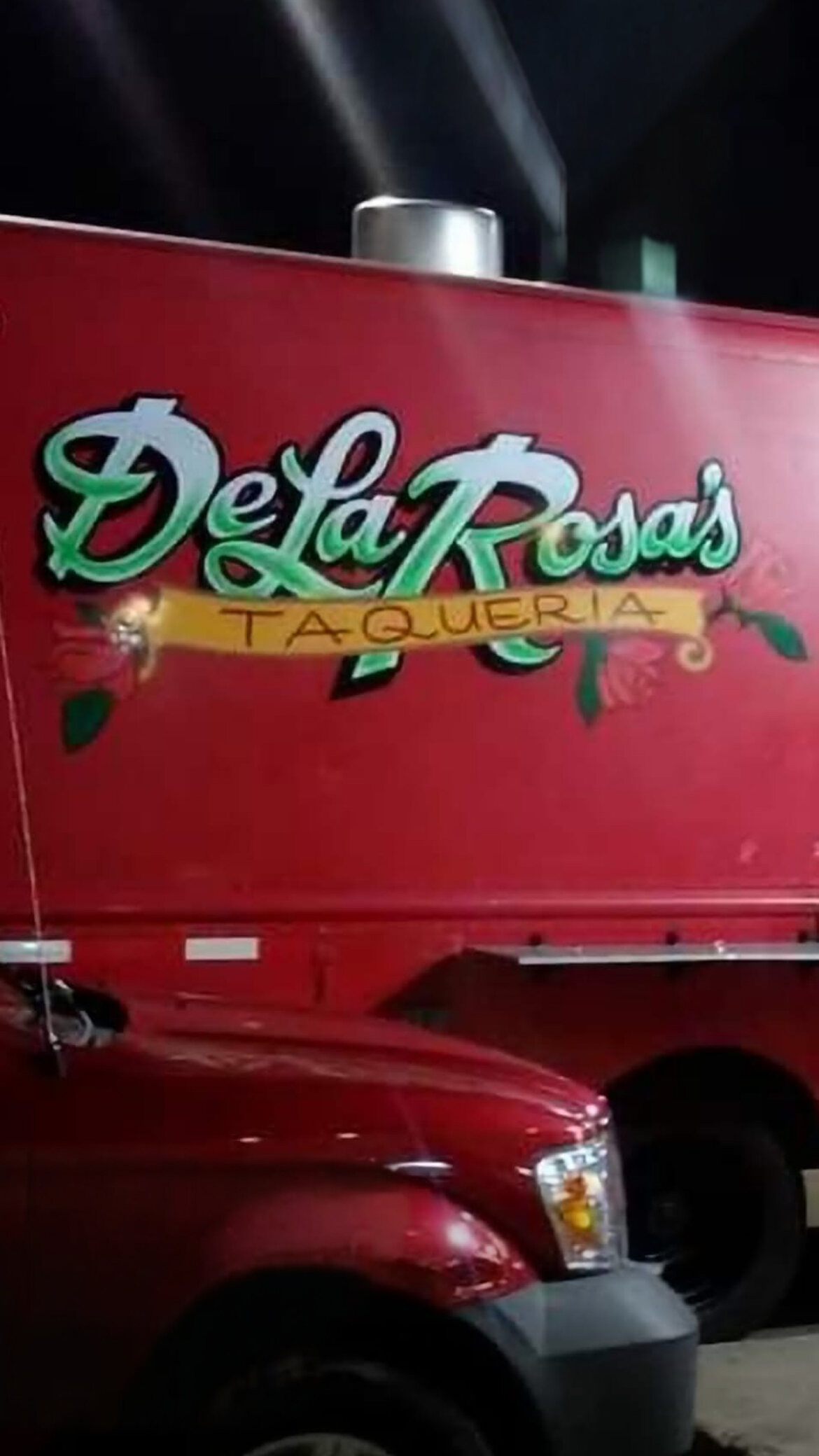 The red De La Rosa's Taqueria food truck at night